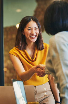 Cheerful businesswomen shaking hands in meeting room
